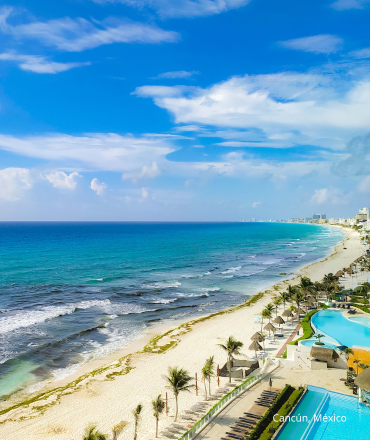 Vista aérea de la costa de Cancún con mar turquesa, playas de arena y cielos despejados.
